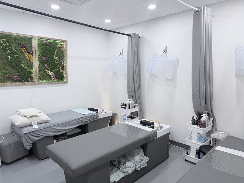 The head spa room at Therapy Nail Spa — treatment beds with overhead Korean rinse units and a preserved moss wall